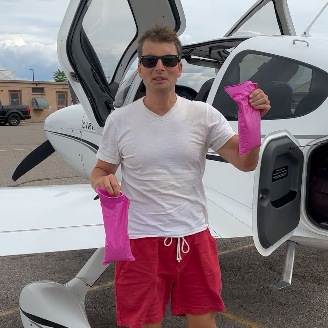 Captain Ilya TS holding two inflight relief bags in front of his Cirrus SR22